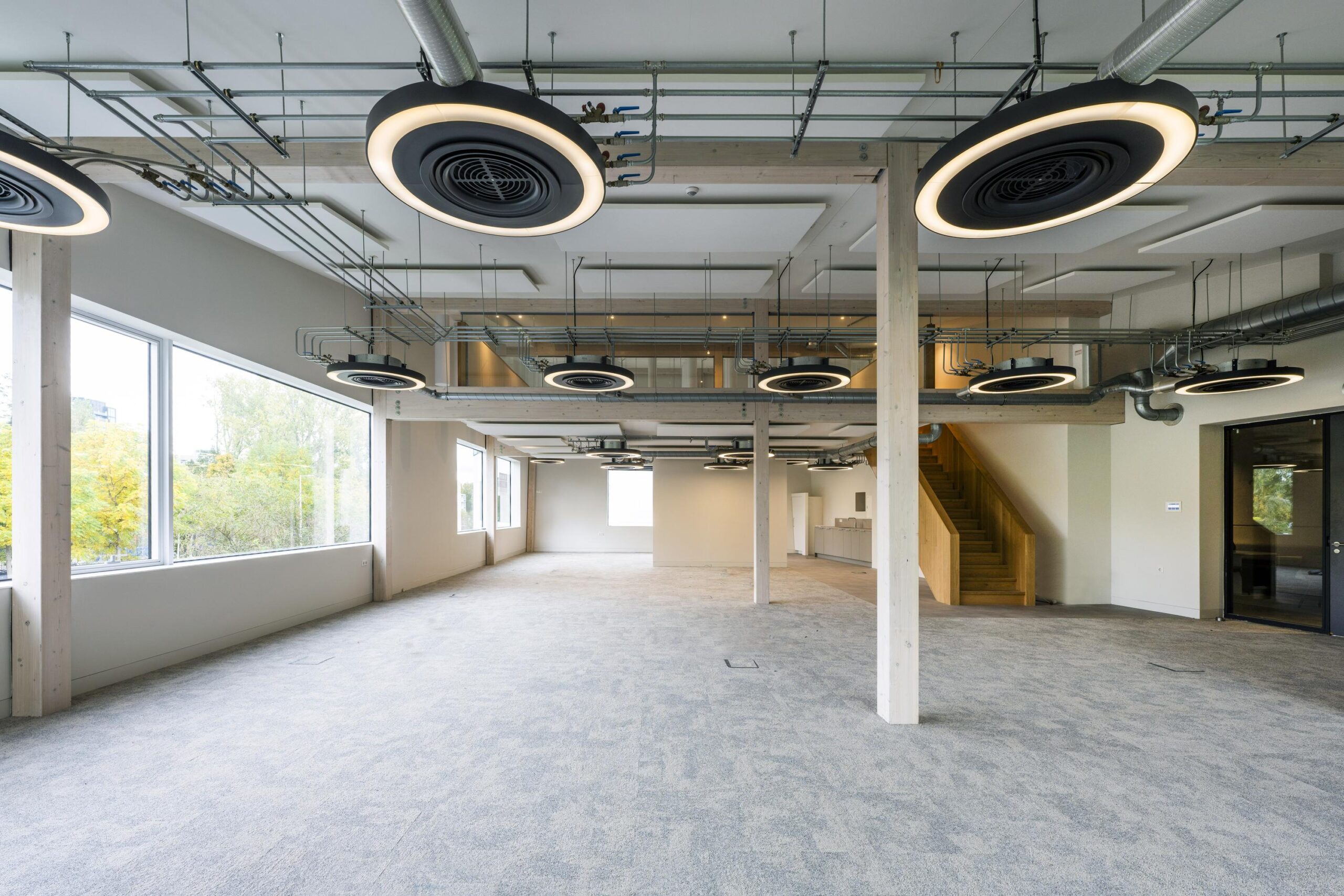 Licht en modern kantoorinterieur aan de Fred. Roeskestraat met grote ramen, zichtbare plafondinstallaties en een houten trap.